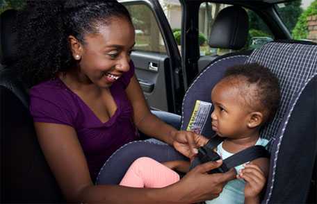 Mother buckling baby into car seat