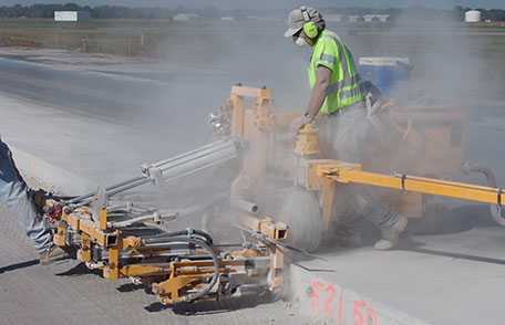 Highway construction worker using dowel drill