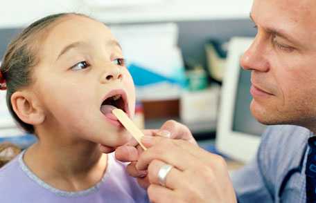 Doctor checking young girl's throat