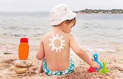 Mother putting sunscreen on son