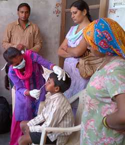 A nurse in India collects a sample from a young boy’s nose as part of a house-to-house surveillance study on influenza vaccine.  