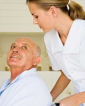 Photo of a female health care professional assisting a senior man in a wheelchair.