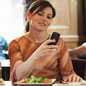 Women at resturant using cell phone. 