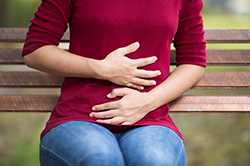 Lady holding stomach on park bench