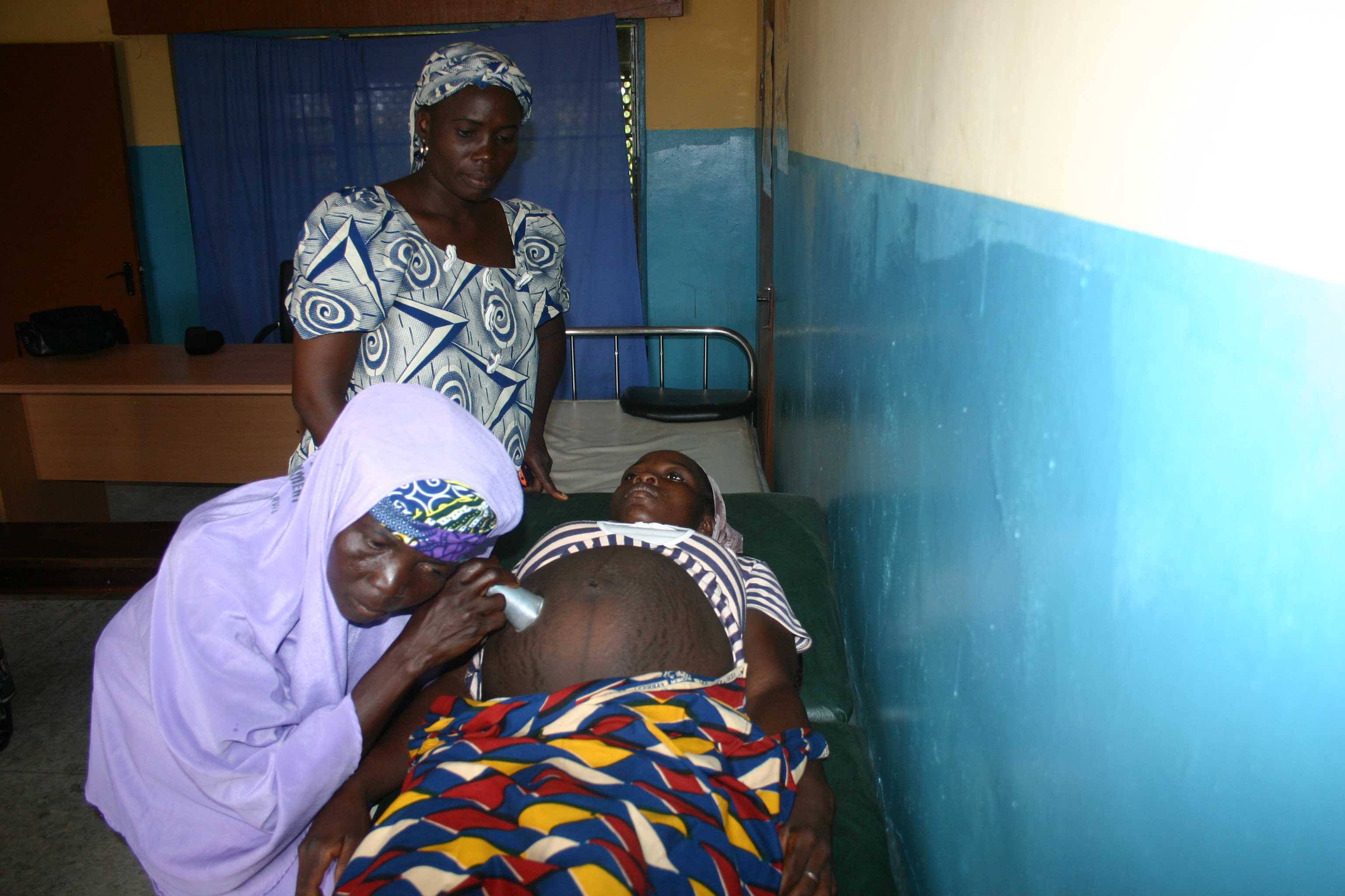 Hauwa Saliu palpating a pregnant woman under the supervision of Mrs. Faustina Ajayi