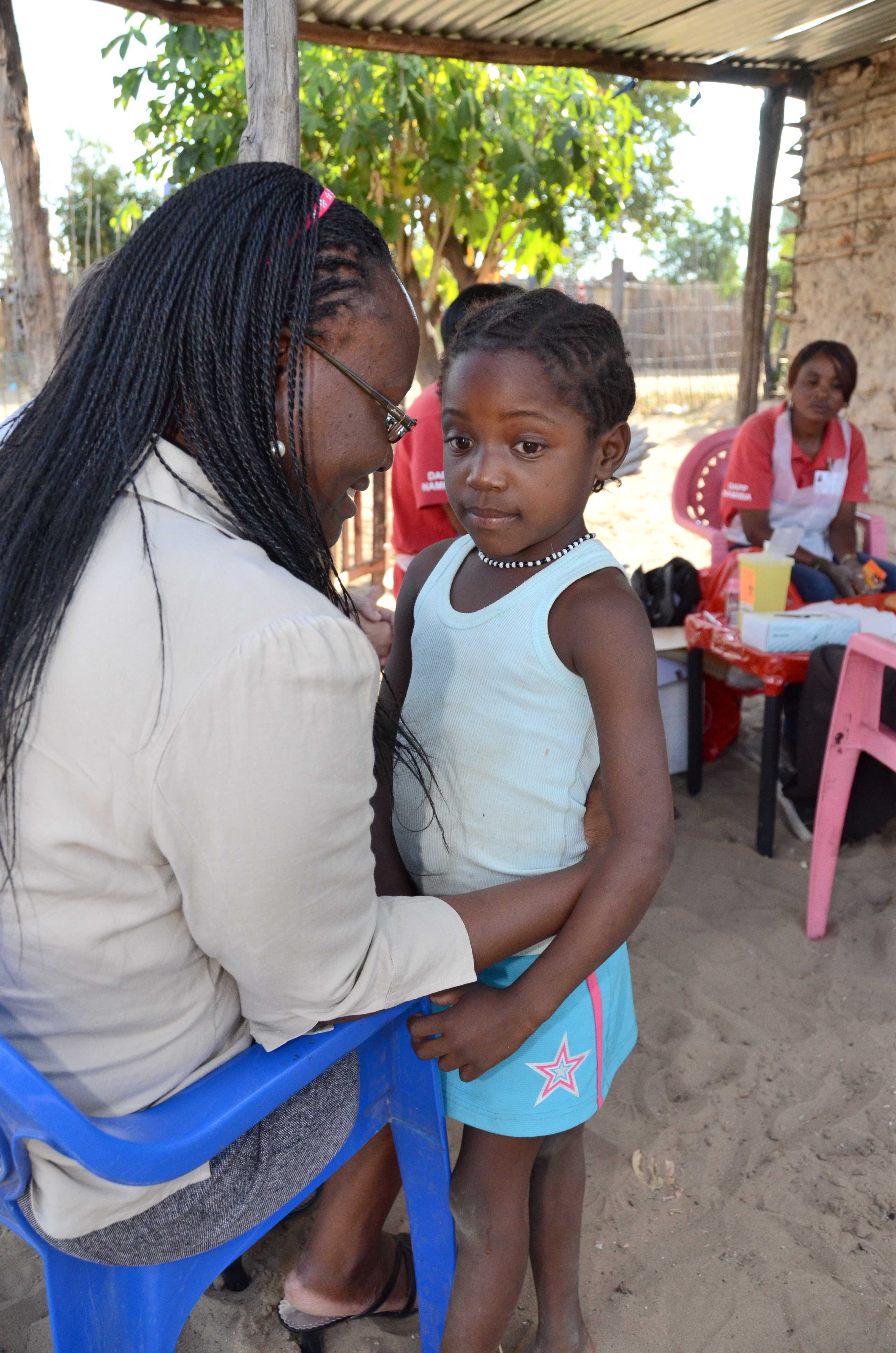 Naemi speaks to a six year old girl while her parents recieve pre-test counseling during a home-based HIV testing session