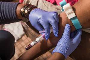 A nurse draws blood from a patient as part of the HIV