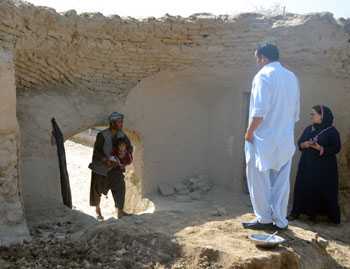 	Afghani man cradles with toddler in his arms as a vaccination team approaches his home.