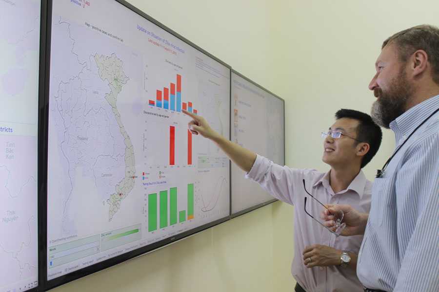 	A photo of the data dashboard with Dr. Tran and Peter Rzeszotarski, CDC Emergency Management Specialist.