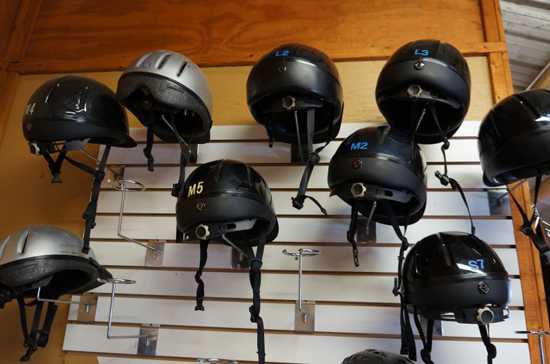 riding helmets hanging on a wall
