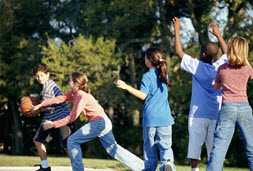 children playing basketball on an outdoor court