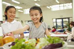 2 elementary school girls looking at healthy food options in the cafeteria