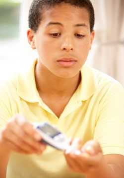 Boy using monitor to check blood sugar level