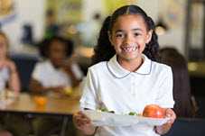 Young girl smiling, holding plate of food