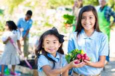 Two young girls holding fruit