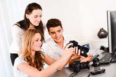 Three people inspecting a camera