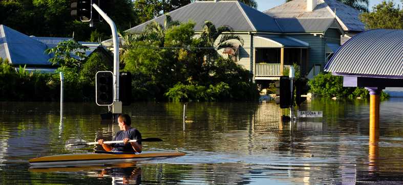 a man canoeing in a boat down a flooded street