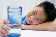 	Young boy looking at a glass of water.