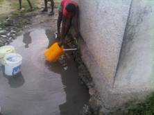 Person pouring water from a public water source into a petrol container.