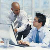 photo of two men in business attire in looking at a computer