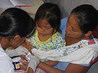 A young girl in Iquitos, Peru, has a blood smear taken by medical technician to determine if she has malaria.