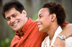 Father and son smiling with dad's arm around his son's shoulders. 