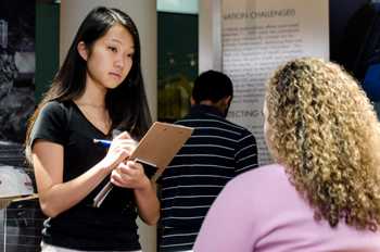 Two girls facing each other while one takes notes