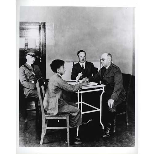 National Library of Medicine; photograph by P.E. Brooks  -  U.S. Public Health Service (PHS) and Immigration Service officers interrogating a Chinese immigrant, Angel Island, California, 1923  -  Asian immigrants who arrived the first part of the 20th century received special scrutiny because they were considered disease carriers. The Asian community mounted many legal challenges to these practices. 