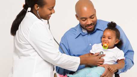 A father holding his daughter at a doctor's visit