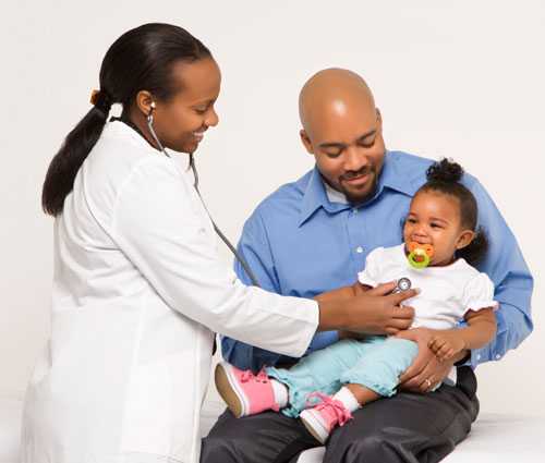 A father holding his daughter at her doctor visit