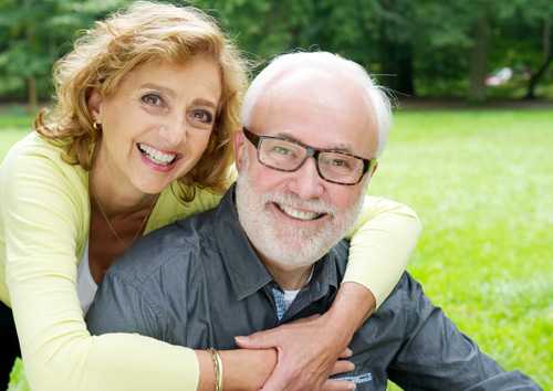 Couple sitting in the grass smiling.