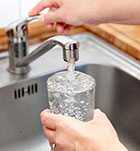 Photo of a woman's hands getting water from a kitchen faucet.