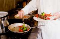 Photo of a cook preparing a plate of food.