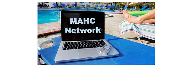 Photo of a laptop by a poolside with a person sunbathing beside it.