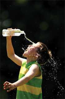 Young boy pouring water on his head to cool himself.