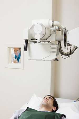 Image of patient having x-ray with technician behind barrier