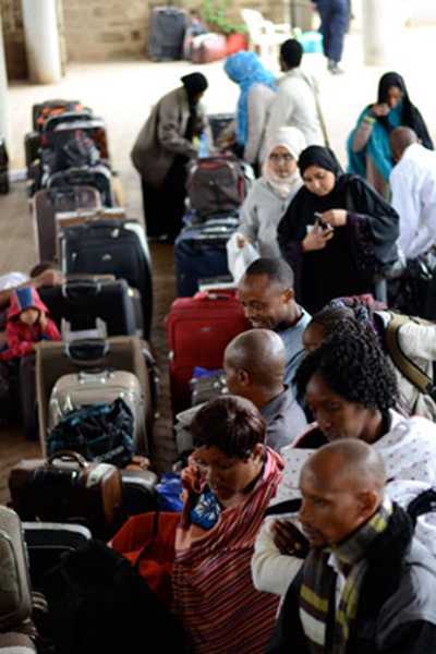 Refugees line up with suitcases to board an airplane.