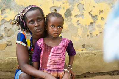 A woman sits with her arms around her young child