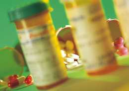 prescription containers with blurred labels surround by pills on a counter top