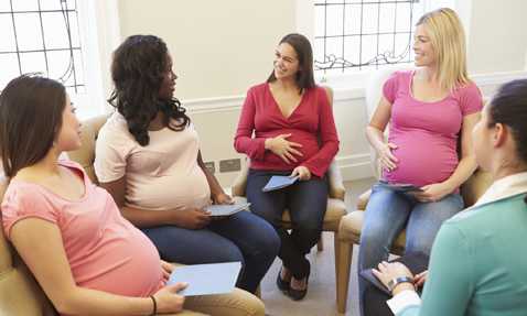 Group of pregnant women sitting in chairs, circled together 