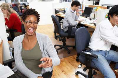 People in office area, woman laughing.