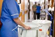 Torso of a hospital cleaner pushing bins