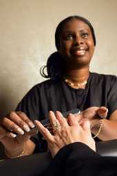 A manicurist smiles as she files her customer’s fingernails