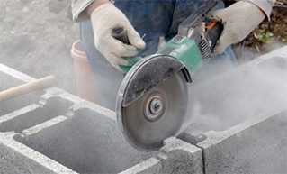 Worker cutting through bricks.