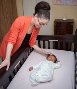 Lady caring for baby in crib