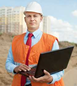 Trabajador en sitio de construcción con una computadora portátil.