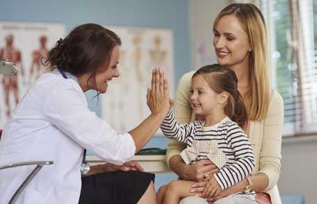 Doctora con una niña pequeña acompañada de su madre