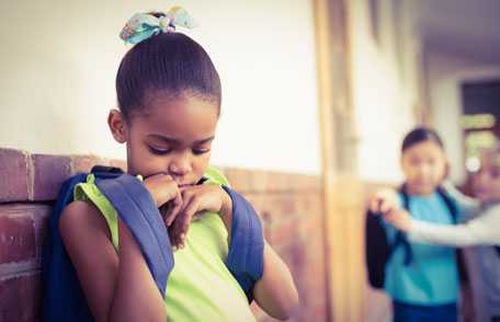 Niña triste alejada de niños que le apuntan