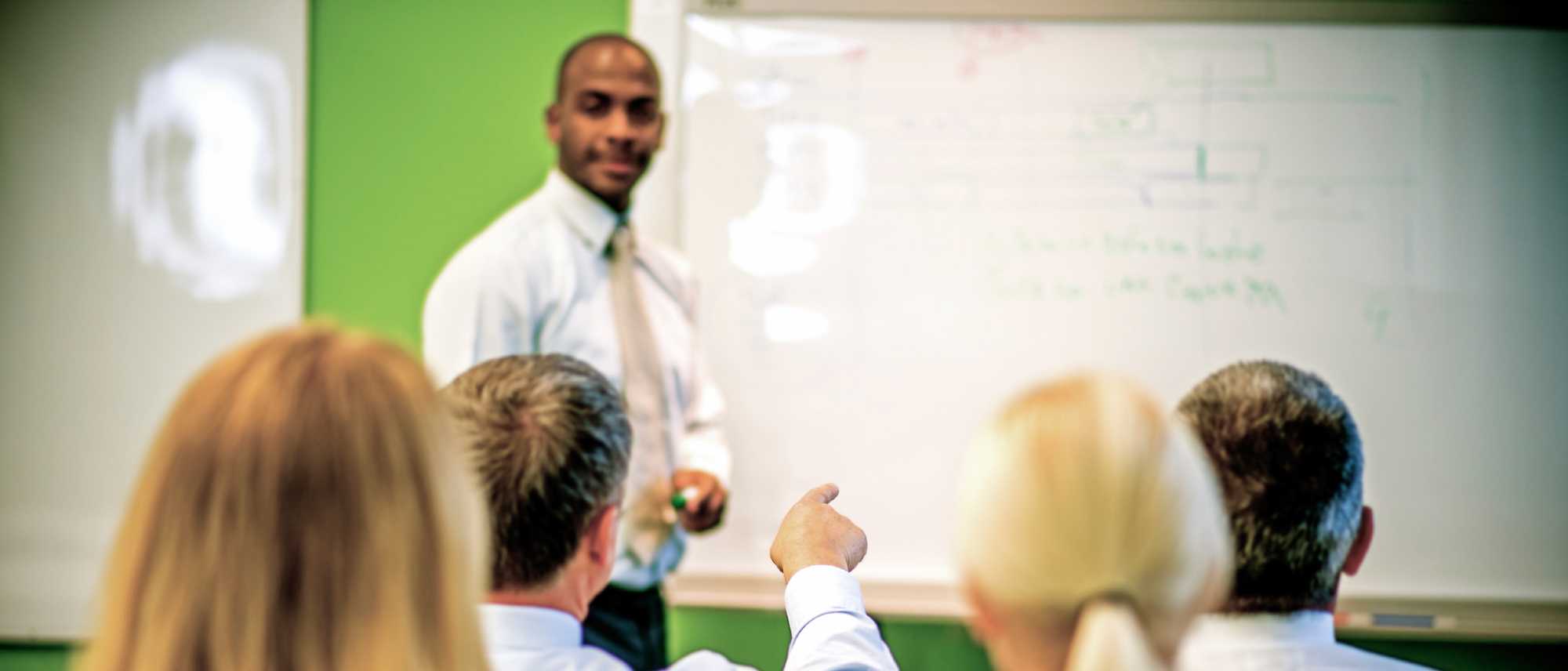 teacher at a blackboard and adult students