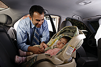 Dad buckling baby in a baby seat.